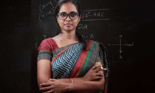 Portrait of an Indian lady teacher stands in front of a blackboard